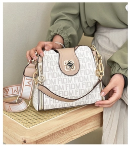 Détail du sac à main beige imprimé FIDM avec fermoir floral doré et bandoulière
