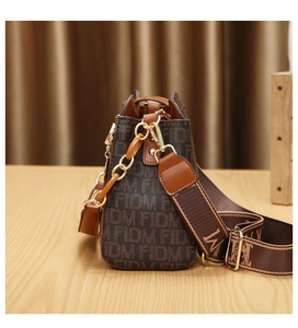 Détail d'un sac vintage marron à monogramme FIDM avec boucle dorée et bandoulière