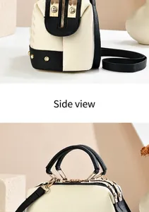 Detail of two-tone cream and black handbag with pearl studs and gold-tone hardware