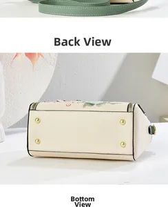 Detailed view of floral embroidery on cream leather bag with golden metal base studs