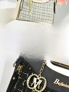 Detailed view of woven tweed texture with gold M pendant and leather trim on handbag