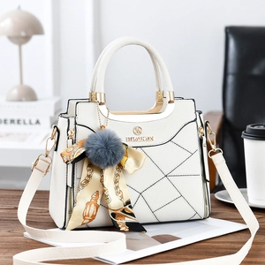 Detail of white tote bag showing lychee grain leather, grid stitching and fur ball charm