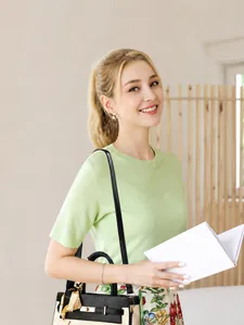 Détail d'un sac à main chic noir et blanc avec un foulard en soie jaune sur la poignée