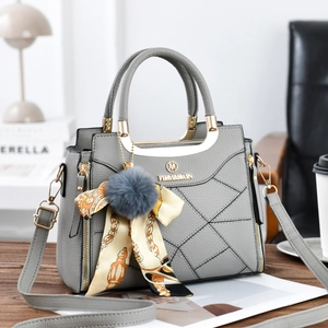 Detailed view of grey textured leather handbag with plush ball and silk scarf charm
