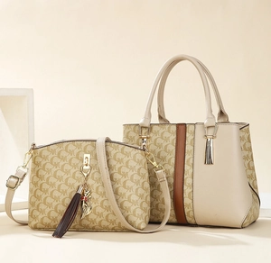 Detail of two-piece handbag set with monogram pattern, tassel and golden cat charm