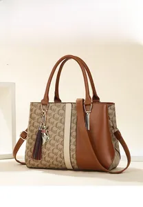 Detail view of two-piece handbag set in brown leather and patterned fabric with gold charm
