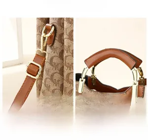 Close-up of golden metal hardware and brown leather handles on a patterned tote bag