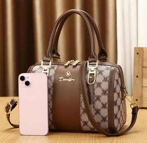 Detail shot of mini Boston bag showing patterned fabric and size relative to a phone