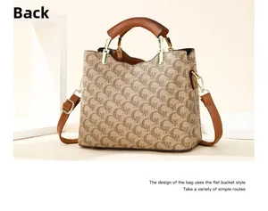 Detail view of the flat bucket handbag showing brown monogram pattern and leather handle