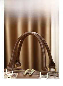 Close-up of durable leather handles and gold-tone zipper on monogram print handbag