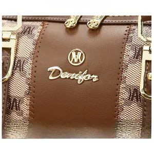 Close-up of premium gold hardware and brown litchi grain leather on a satchel bag