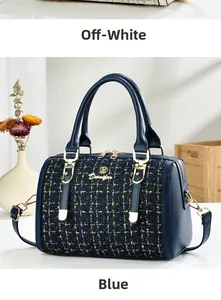 Detail of blue woven fabric Boston bag with gold hardware and leather trim handle