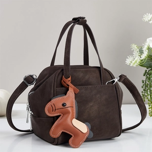 Detailed view of dark brown faux leather handbag featuring a cute horse charm and stitching