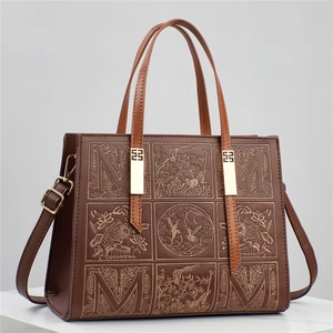 Détail du sac à main marron avec broderie quadrillée, lettre M majuscule et motifs floraux