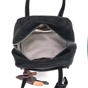Top view of black tote bag interior featuring herringbone lining and pony charm accessory
