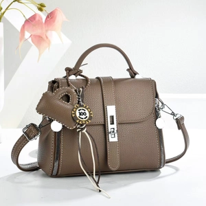 Close-up of brown lychee grain leather handbag with silver hardware and charm detail