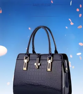 Macro view of blue faux crocodile texture and gold hardware on the tote bag