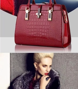 Close-up of glossy burgundy crocodile embossed handbag with luxury gold hardware