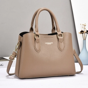 Detail of khaki pebbled leather handbag featuring gold hardware and logo branding