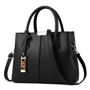 Détail du sac à main en cuir noir avec ferrures dorées et pendentif logo décoratif
