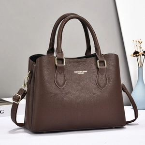 Detail of dark brown lychee leather handbag showing gold hardware and texture