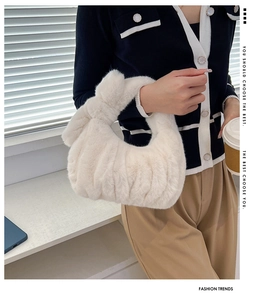Detail of white plush handbag featuring fluffy pleated design and soft faux fur texture