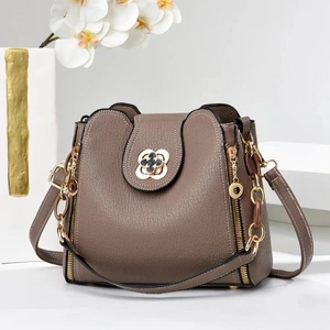 Détail du sac à main en cuir taupe avec fermoir fleur et breloque en chaîne dorée