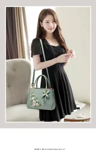 Detail of mint green handbag featuring floral embroidery and elegant leather flower charm