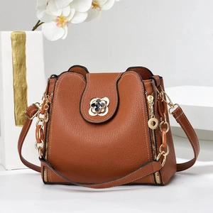 Détail du sac à main en cuir marron avec fermoir fleur dorée et bandoulière chaîne