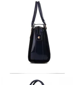Side view detail of glossy croc-embossed leather handbag with gold metal hardware