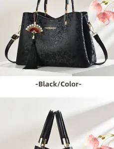 Dettaglio di borsa in pelle nera con goffratura floreale e nappina decorativa