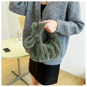 Close-up of fluffy dark green faux fur handbag with stylish rabbit ear knot detail
