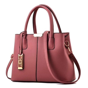 Détail du sac à main rose avec texture cuir, garniture dorée et bandoulière longue