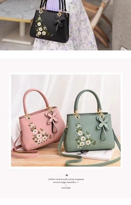 Detail of elegant floral embroidery and heart-shaped gold buckle on Chinese style handbag