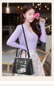 Details der eleganten schwarzen Handtasche mit Lotus-Stickerei und goldenem Herzanhänger