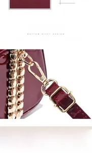Detail of red patent leather handbag showing adjustable gold-tone buckle and lobster clasp