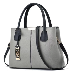 Détail du cuir grainé et du pendentif doré sur le sac à main bicolore pour femme