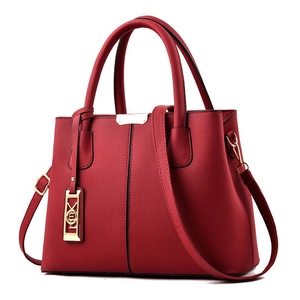 Détail du sac à main rouge en cuir grainé avec finitions dorées et bandoulière