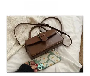 Detailed view of brown PU leather handbag next to smartphone for size comparison
