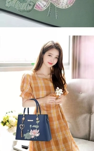 Makroaufnahme der zarten Lotus-Stickerei auf einer dunkelblauen Handtasche im China-Stil
