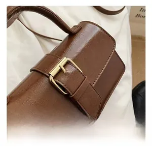 Close-up of vintage dark brown leather bag with detailed golden metal buckle hardware