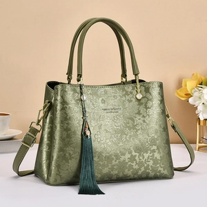 Elegante donkergroene leren handtas met bloemreliëf, handvaten en een kwastje eraan