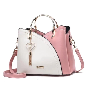 Detail of pink and white crossbody bag with ZZMY metal logo and heart tassel charm