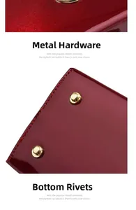 Detail of red glossy patent leather bag with gold hardware plate and protective bottom studs