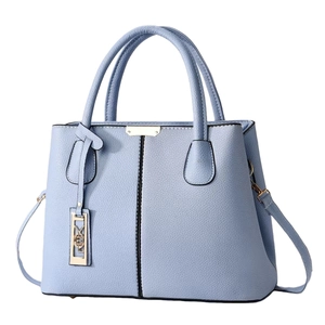 Détail du sac à main en cuir bleu clair avec motif litchi, coutures et breloque dorée