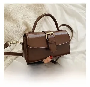 Detailed close-up of brown vintage handbag with golden metal buckle on fabric