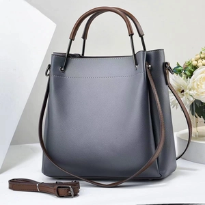 Detail view of large grey-blue tote bag with brown handles and a detachable shoulder strap