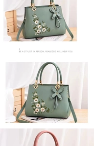Detail of floral embroidery and heart charm on a sage green crossbody handbag