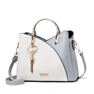 Close-up of color-block leather handbag with gold metal handle and heart tassel charm