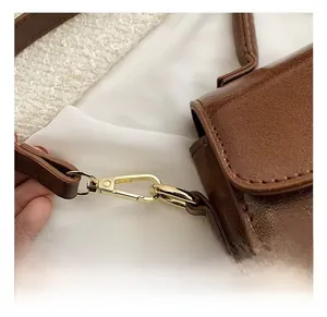 Detail view of premium gold metal hooks and brown leather texture on handbag